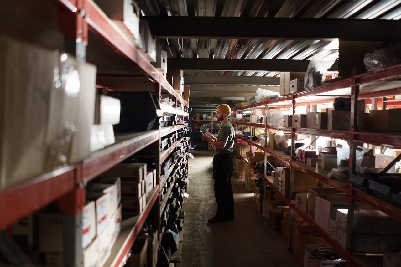 A warehouse worker sorting items on shelves in an organized storage space.